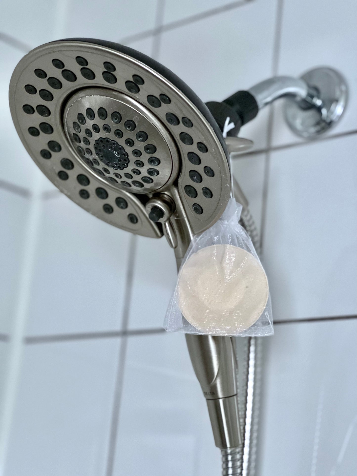 shower steamer in bag hanging from shower head