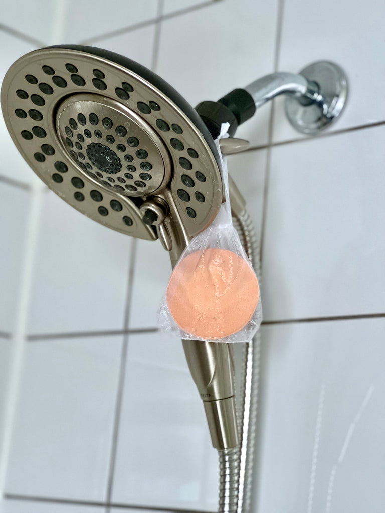 clarity shower soother hanging on shower head orange